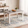 A dining table with fruit on it, placed on a rug in a room with curtains and a sideboard. Produktbild-Vorschau