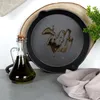 A cast iron pan with oil in it, a bottle of oil, and a plant. Produktbild-Vorschau