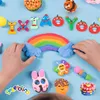 Children's hands are shown arranging colorful playdough creations on a blue background, including a rainbow, animals, and letters. Produktbild-Vorschau