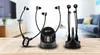 Two sets of wireless headphones and their charging docks are displayed on a wooden table in a living room setting. Produktbild-Vorschau