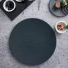 A dark slate plate is centered on a speckled gray surface, with small bowls of berries and food garnishes arranged around it. Voir les images du produit