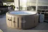 An inflatable hot tub is shown on a tiled patio next to a building with large windows. Produktbild-Vorschau