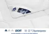 A close-up of a white quilted blanket with a label showing a brand logo and an artistic image. Produktbild-Vorschau