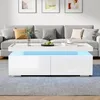 A modern white coffee table with LED lighting in a living room setting, placed in front of a gray sofa. Voir les images du produit