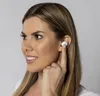 A woman is shown inserting a white wireless earbud into her ear. Náhľad obrázku produktu