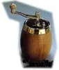 A wooden pepper mill with a brass accent and handle sits on a surface with peppercorns scattered around it. Produktbild-Vorschau