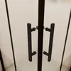 A close-up view of a shower door with black handles. Produktbild-Vorschau