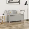 A gray wooden storage bench with a cushion is placed in a room with a side table and a floor lamp. Náhľad obrázku produktu