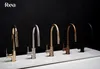 A line of five kitchen faucets in different finishes displayed on a white surface against a black background. Produktbild-Vorschau