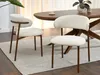 Two beige upholstered dining chairs are placed around a wooden dining table in a well-lit room. Voir les images du produit