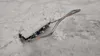 A snow shovel is partially buried in snow and ice. Produktbild-Vorschau