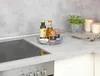 A kitchen counter with a stove, a rotating tray with spices and oils, and a potted plant. Produktbild-Vorschau