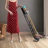 A woman in a polka dot dress stands next to a vacuum cleaner on a stand. Produktbild-Vorschau