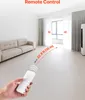 A hand holding a remote control in a modern living room, with a sofa and curtains visible. Náhľad obrázku produktu