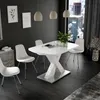A modern dining room with a white extendable table and chairs, set against a dark gray wall and a large window overlooking a city skyline. Anteprima dell’immagine prodotto
