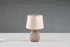 A small table lamp with a textured ceramic base and a fabric shade is placed on a white surface against a gray background. Anteprima dell’immagine prodotto