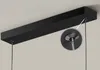 A close-up view of a black rectangular LED pendant light fixture mounted on a ceiling, with a magnified inset showing the detail of a cable attachment. Produktbild-Vorschau