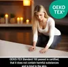A woman is kneeling on a rug in a dimly lit room with candles in the background. Produktbild-Vorschau