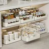 Kitchen cabinet shelves organized with pull-out drawers containing various kitchen items like jars, bowls, and cookware. Produktbild-Vorschau