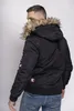 A man wearing a black hooded winter jacket and blue jeans, shown from the back and side. Náhled obrázku produktu