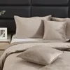 A close-up view of a bed with beige quilted bedding and pillows. Podgląd zdjęcia produktu