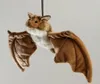 A plush toy bat is hanging against a plain background. Voir les images du produit