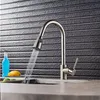 A kitchen faucet with water running into a sink, with a bottle and fruit in the background. Náhľad obrázku produktu