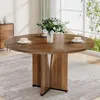 A round wooden dining table set with cups and a vase of flowers, placed on a rug in a room with a large window. Voir les images du produit