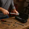 A person is using a torque wrench on a wooden workbench with other tools and hardware scattered around. Anteprima dell’immagine prodotto