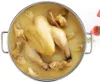 A whole chicken is submerged in a light yellow broth inside a silver pot. Náhled obrázku produktu