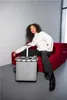A woman sits on a red sofa next to a grey shopping trolley. Produktbild-Vorschau