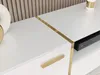 A close-up view of a white sideboard with gold accents and a gold handle. Voir les images du produit