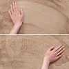 A close-up of a hand touching a textured beige carpet. Podgląd zdjęcia produktu