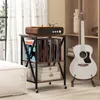 A record player stand with vinyl records and decorative boxes, next to a guitar on a stand, in a living room setting. Produktbild-Vorschau