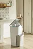 A white trash can with a lid open, filled with paper waste, is placed in a kitchen setting next to a counter with plates and glasses. Náhľad obrázku produktu