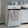 A bathroom cabinet with a drawer and a laundry hamper, with toiletries on top and a towel hanging from the hamper. Produktbild-Vorschau