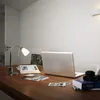 A desk with a laptop, camera, photos, and a lamp. Anteprima dell’immagine prodotto