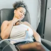 A woman is sitting in a chair holding a baby. Produktbild-Vorschau