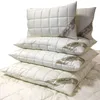 A stack of white pillows on a white quilted surface. Produktbild-Vorschau