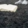 An open book and a pair of slippers are placed on a fluffy gray carpet. Anteprima dell’immagine prodotto