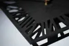 A close-up, angled view of a black wall clock with a decorative cut-out pattern along the edge. Anteprima dell’immagine prodotto