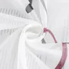 A close-up view of a white sheer curtain with a printed pattern of text and violet lines. Produktbild-Vorschau