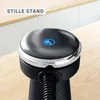 Close-up of the top of a black appliance with a silver rim and a blue illuminated icon, placed on a wooden surface with a blurred kitchen background. Produktbild-Vorschau