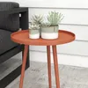 A small, round, red side table with three plants in pots on top, placed next to a dark gray outdoor chair. Produktbild-Vorschau
