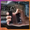 A hand holding a grip strengthener in a gym setting. Podgląd zdjęcia produktu