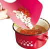 A hand is tilting a pink cutting board over a red pot, pouring chopped vegetables and mushrooms into the pot. Voir les images du produit