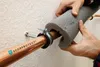 A person is installing pipe insulation on a copper pipe. Produktbild-Vorschau