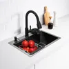A black kitchen sink with a faucet and apples inside, set on a white countertop with a white tiled backsplash. Podgląd zdjęcia produktu