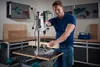 A man is using a drill press in a workshop. Náhľad obrázku produktu