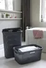 Two dark gray woven laundry baskets are shown in a bathroom setting next to a bathtub. Produktbild-Vorschau